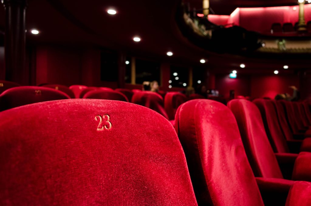 Sala kinowa. Na pierwszym planie trzy czerwone fotele. Na pierwszym od lewej widnieje liczba 23