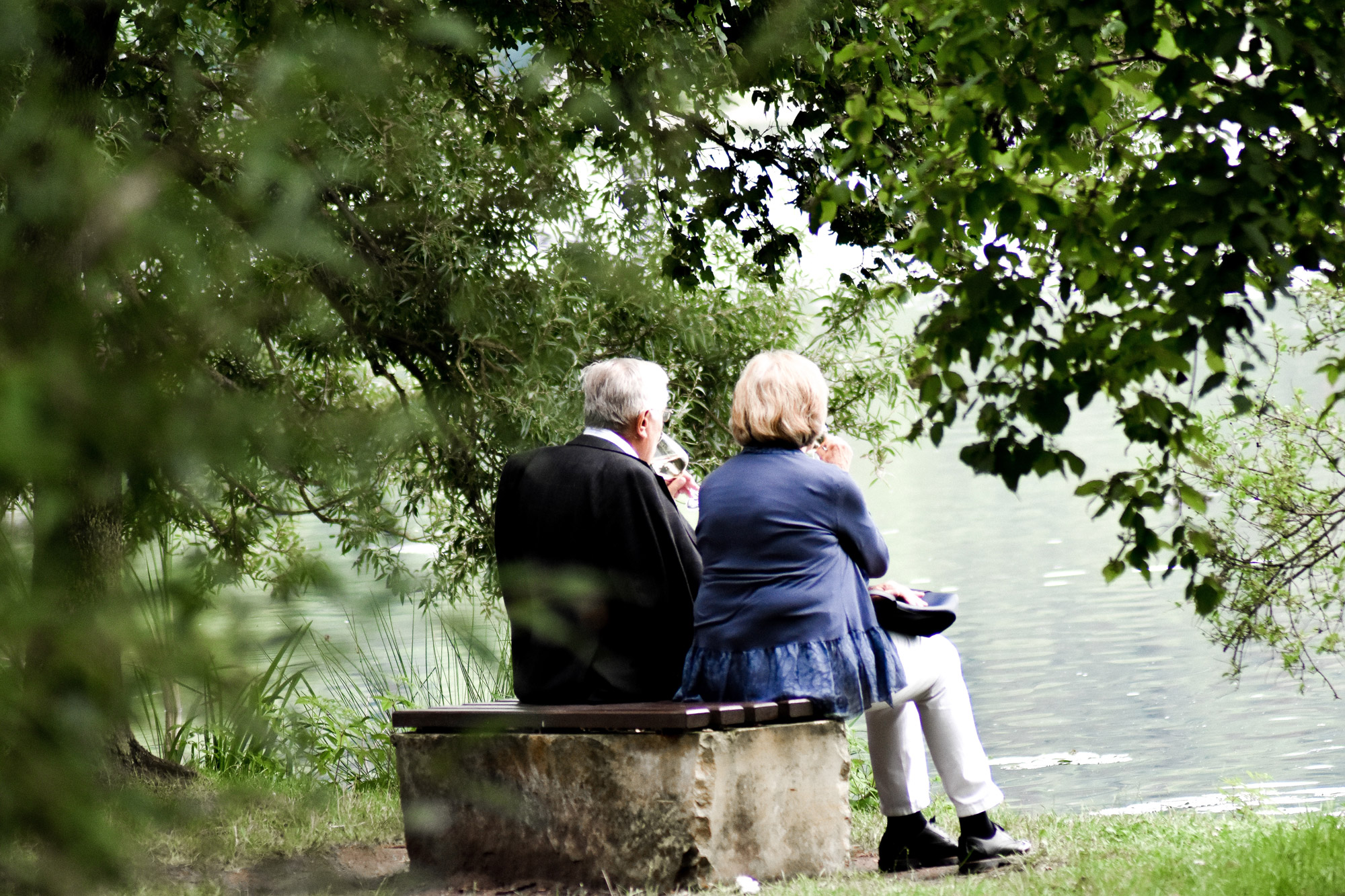 Para seniorów - kobieta i mężczyzna - siedzą na ławce w parku.
