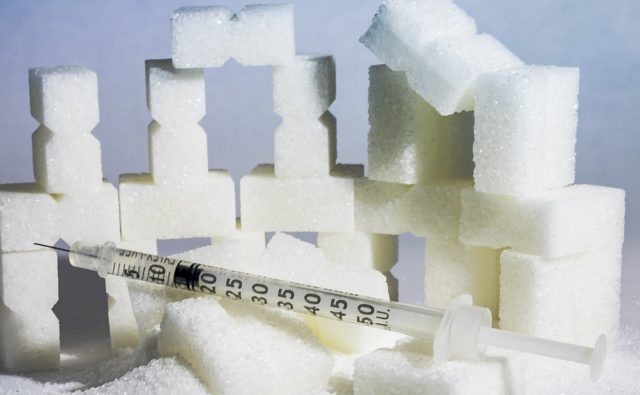 Kostki cukru a obok nich strzykawka z insuliną