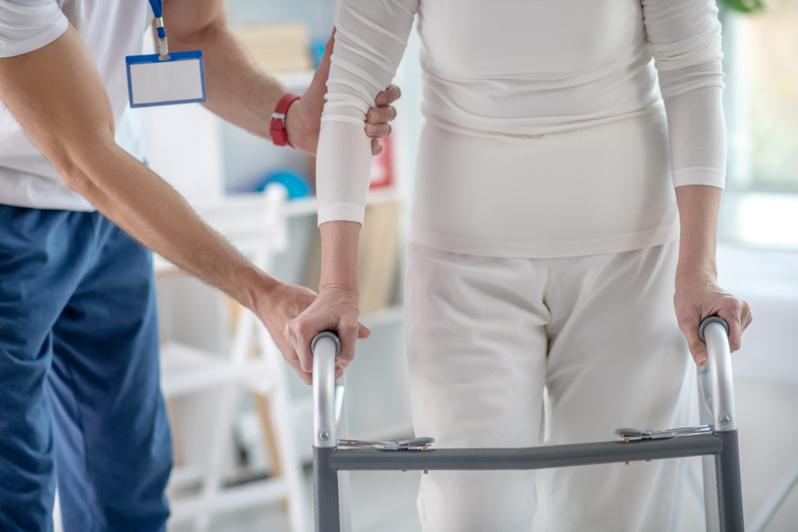 Pacjentka chodzi używając chodzika a asystuje jej rehabilitant