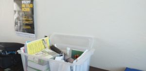 W pudełku leżą materiały potrzebne do przeprowadzenia szkolenia: białe laski, czasopisma PZN, leki z napisami w brajlu.