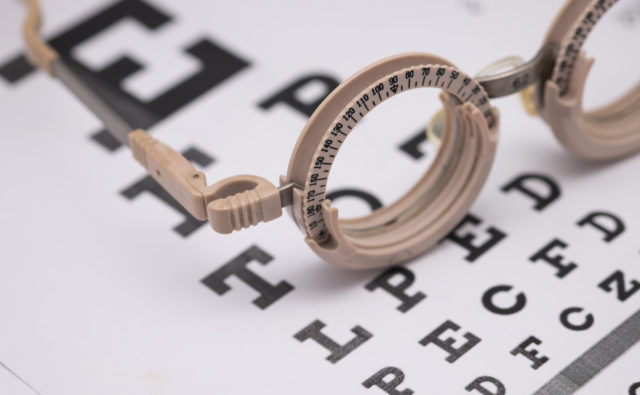 Na tablicy Snellena (okulistycznej) leżą okulary do badania wzroku.