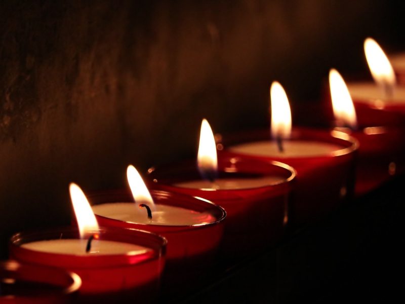 Rząd zapalonych świeczek na ciemnym tle