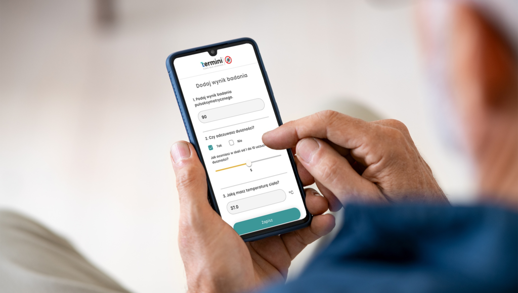 zbliżenie na ręce mężczyzny, który trzyma telefon z aplikacją COVID.Termini.app, widzimy go od tyłu