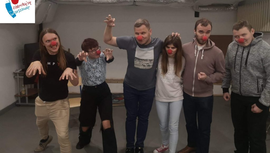 Sześciu aktorów Teatru Krzesiwo. Na nosach mają założone czerwone piłeczki. Troje z nich wyciąga przed siebie ręce.