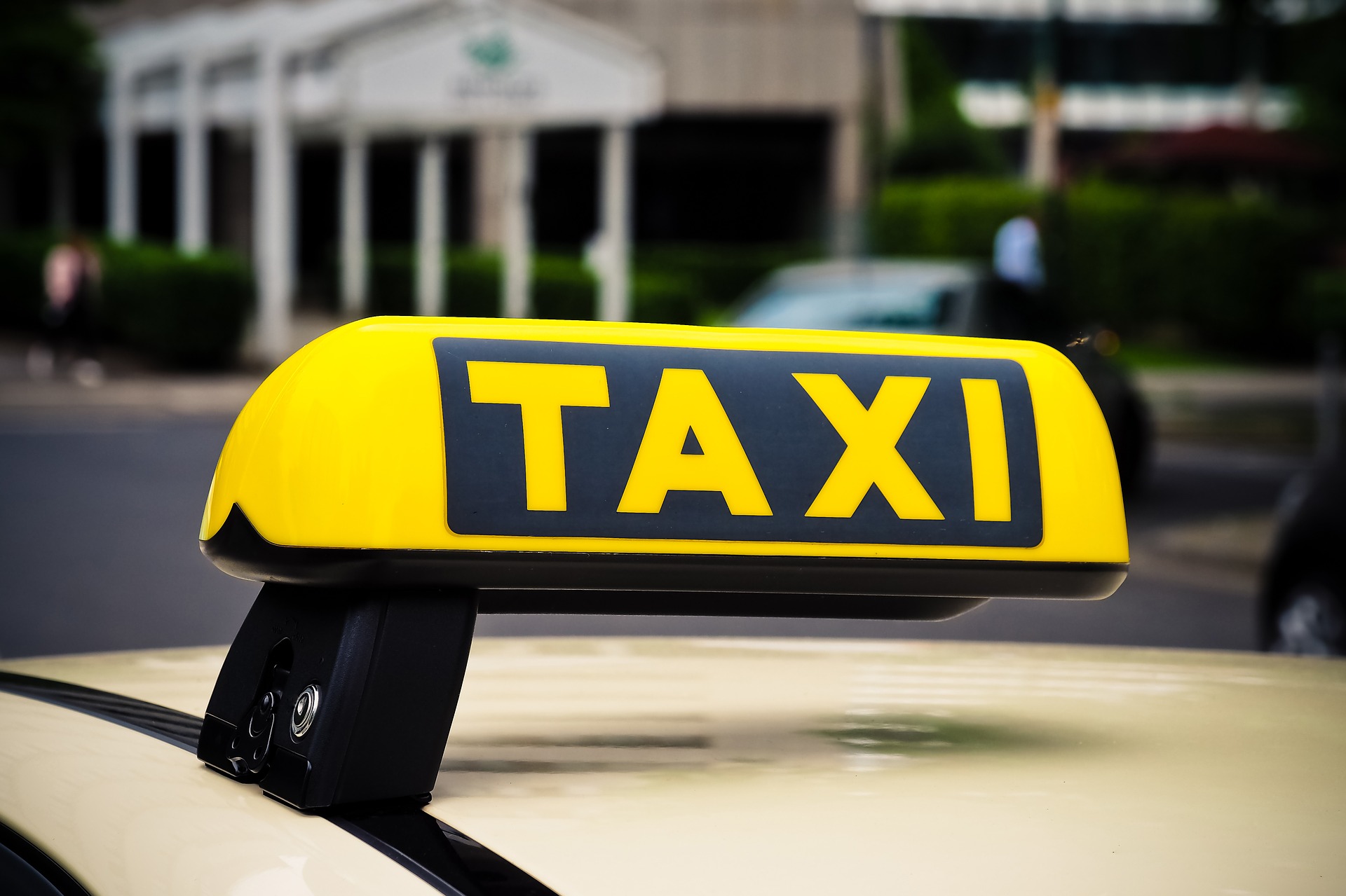 Do dachu samochodu przyczepiony żółto-czarny napis TAXI (żółte litery na czarnym tle).