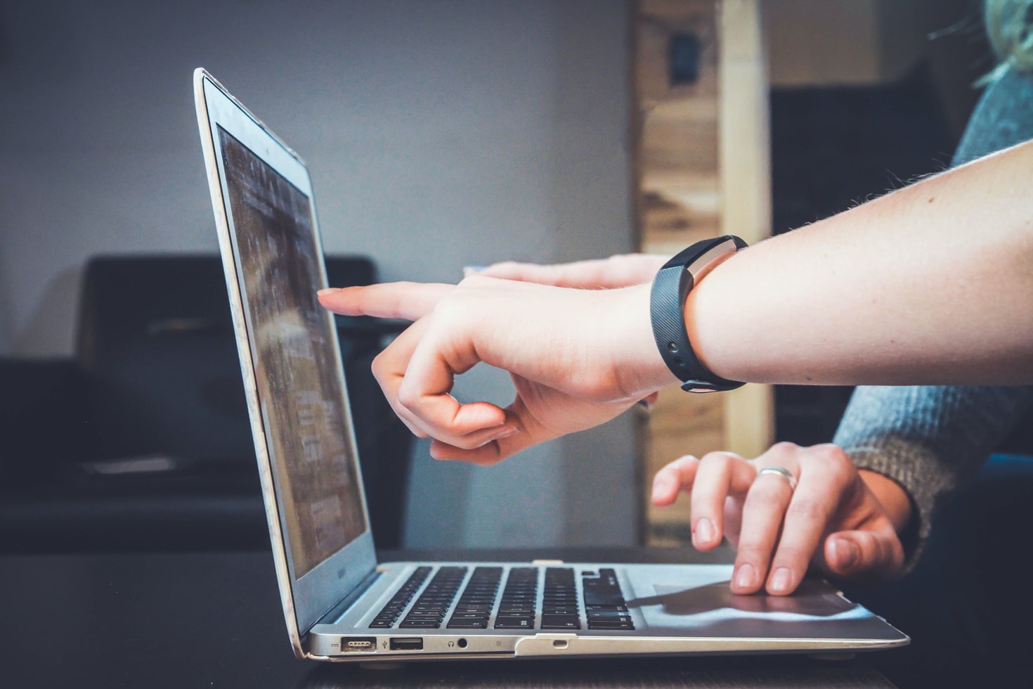 Osoba wskazuje palcem coś na ekranie laptopa
