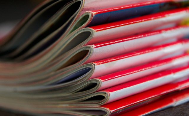 stos kolorowych czasopism ułożone czerwonymi grzbietami