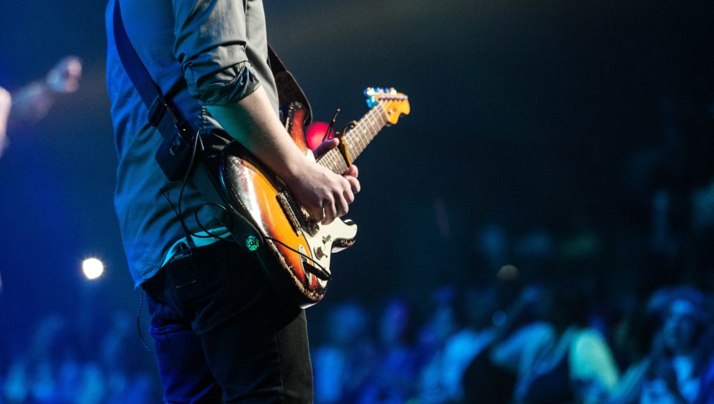 Muzyk z gitarą gra na scenie w trakcie koncertu
