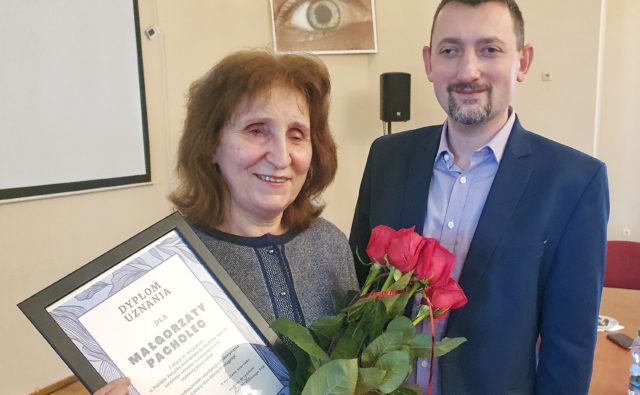 Małgorzata Pacholec z dyplomem i kwiatami, obok prezes Andrzej Brzeziński