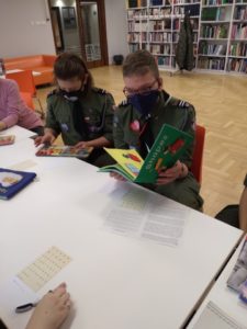 Harcerze przeglądają ksiązki z brajlem