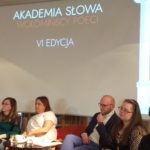 poeci siedzą przy stolikach, za nimi slajd z napisem "Akademia słowa. Wołomińscy poeci. VI edycja"