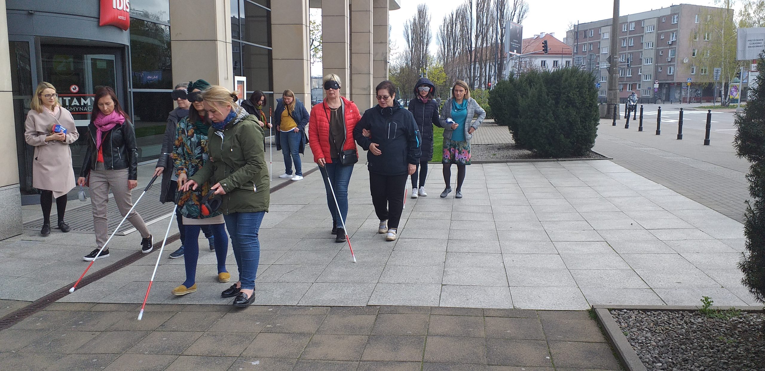 Uczestnicy szkolenia idą z zasłoniętymi oczami i białą laską