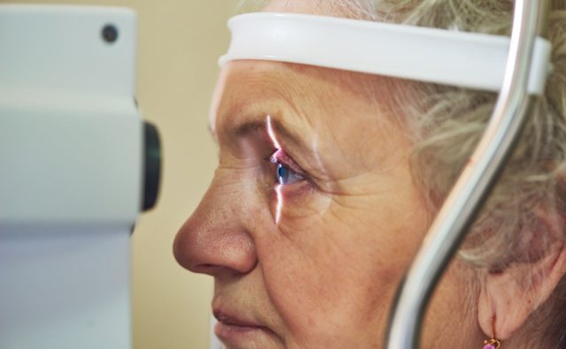 starsza kobieta jest poddawana badaniu wzroku, patrzy w aparaturę