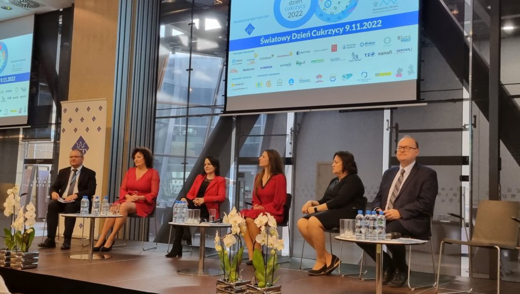 od lewej siedzą: min. Maciej Miłkowski, dr Beata Stepanow, dr Katarzyna Cyranka, poseł Ewa Kołodziej, Jolanta Michałowska oraz prof. Leszek Czupryniak; nad nimi ekran z plakatem promocyjnym Światowego Dnia Cukrzycy