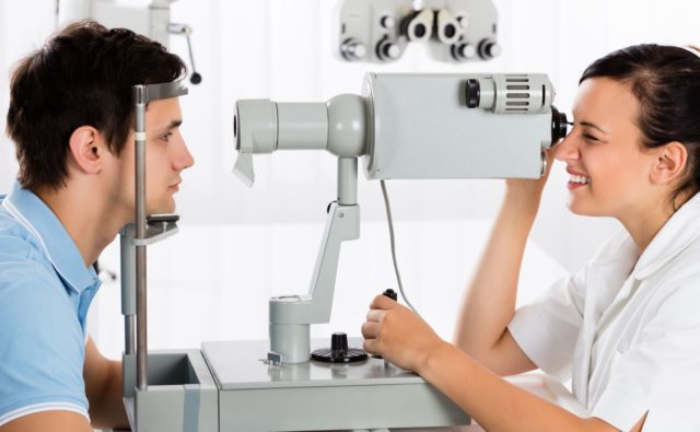 Okulistka bada wzrok pacjenta przy pomocy aparatu