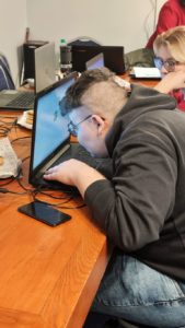Młody mężczyzna siedzi przy stole z laptopem. Pracuje nad budżetem domowym na pliku w Excelu. 