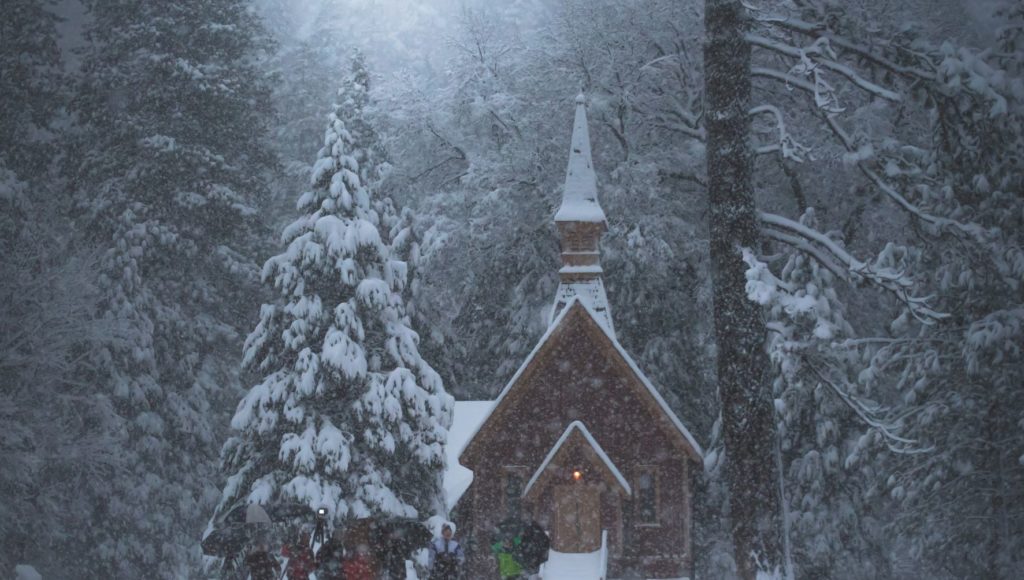 Zima pada śnieg, w oddali mały kościół przed nim dzieci