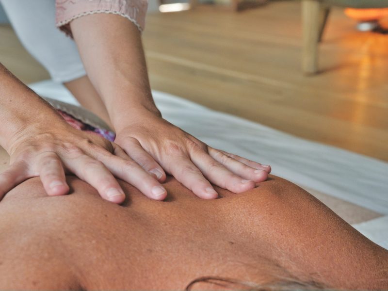 Dłonie masażysty wykonują masaż pleców.