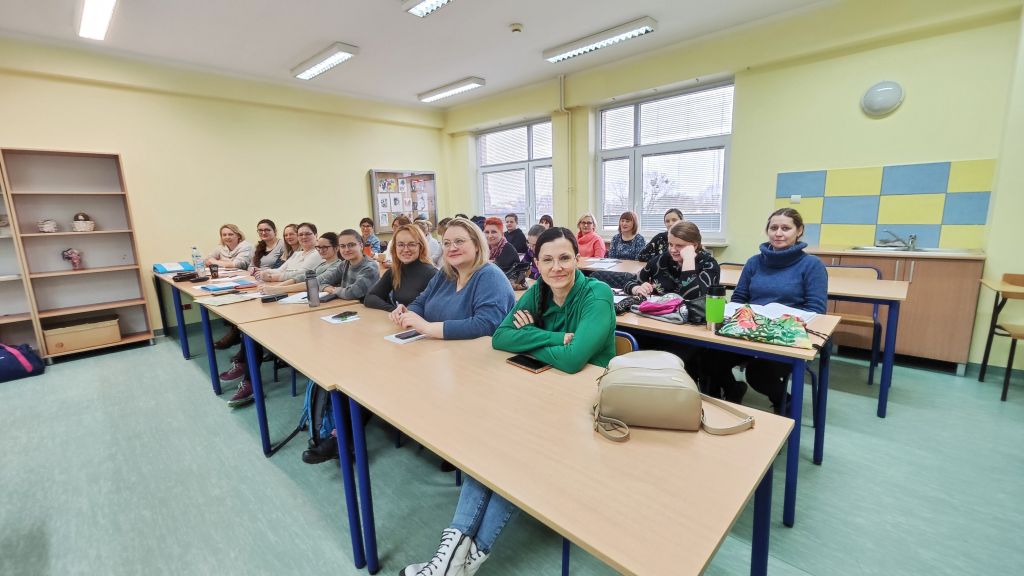 Uczestniczki szkolenia siedzą w ławkach. Uśmiechają się do zdjęcia.