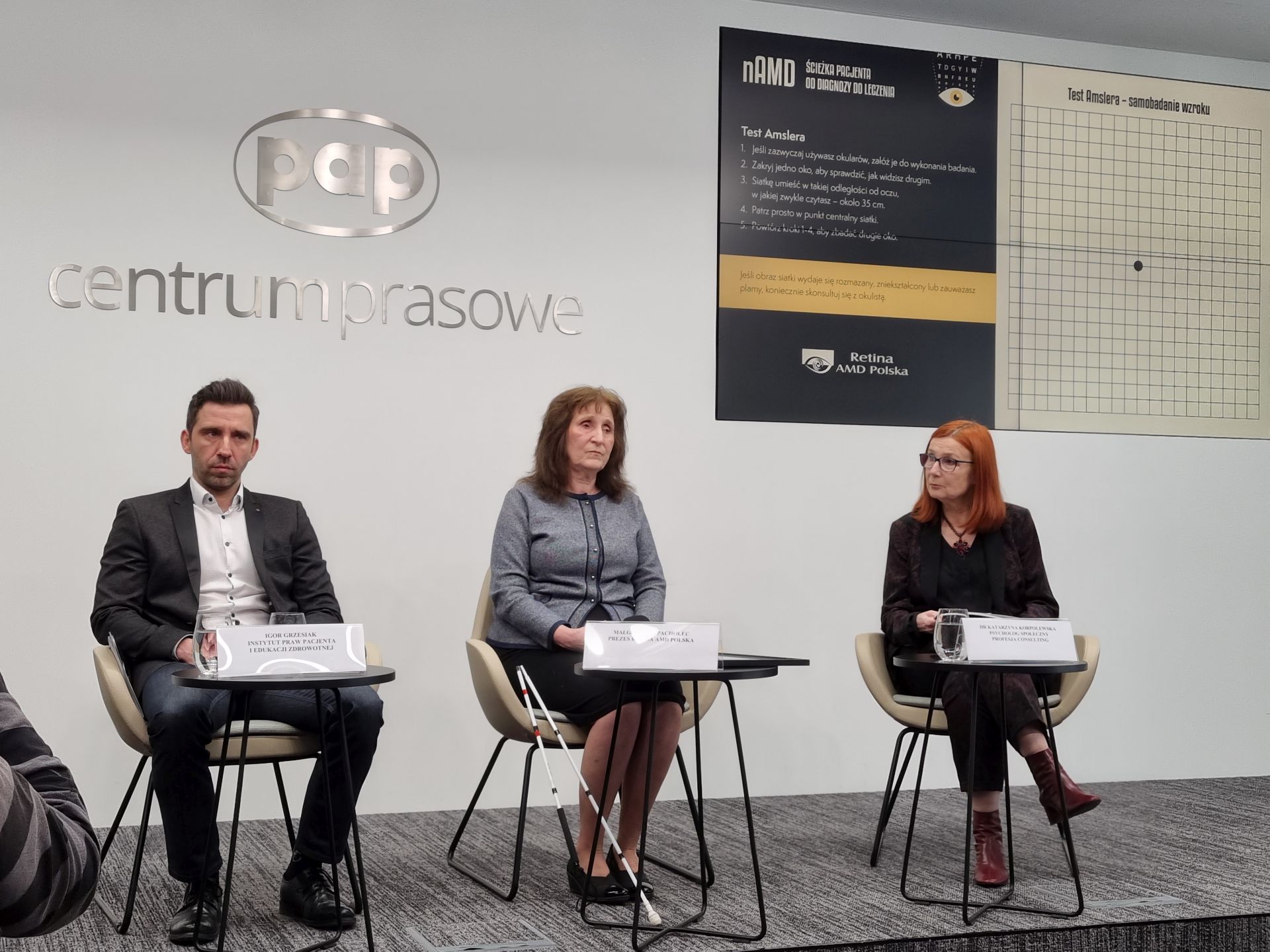 od lewej siedzą: Igor Grzesiak z Instytuty Praw Pacjenta i Edukacji Zdrowotnej, Małgorzata Pacholec ze Stowarzyszenia Retina AMD Polska i dr Katarzyna Korpolewska, psycholog; za nimi ekran z testem Amslera