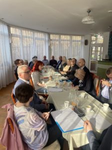 Uczestnicy szkolenia siedzą wspólnie przy stole. Niektórzy z nich robią notatki ze spotkania.