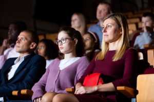 Widzowie patrzą na film w sali kinowej