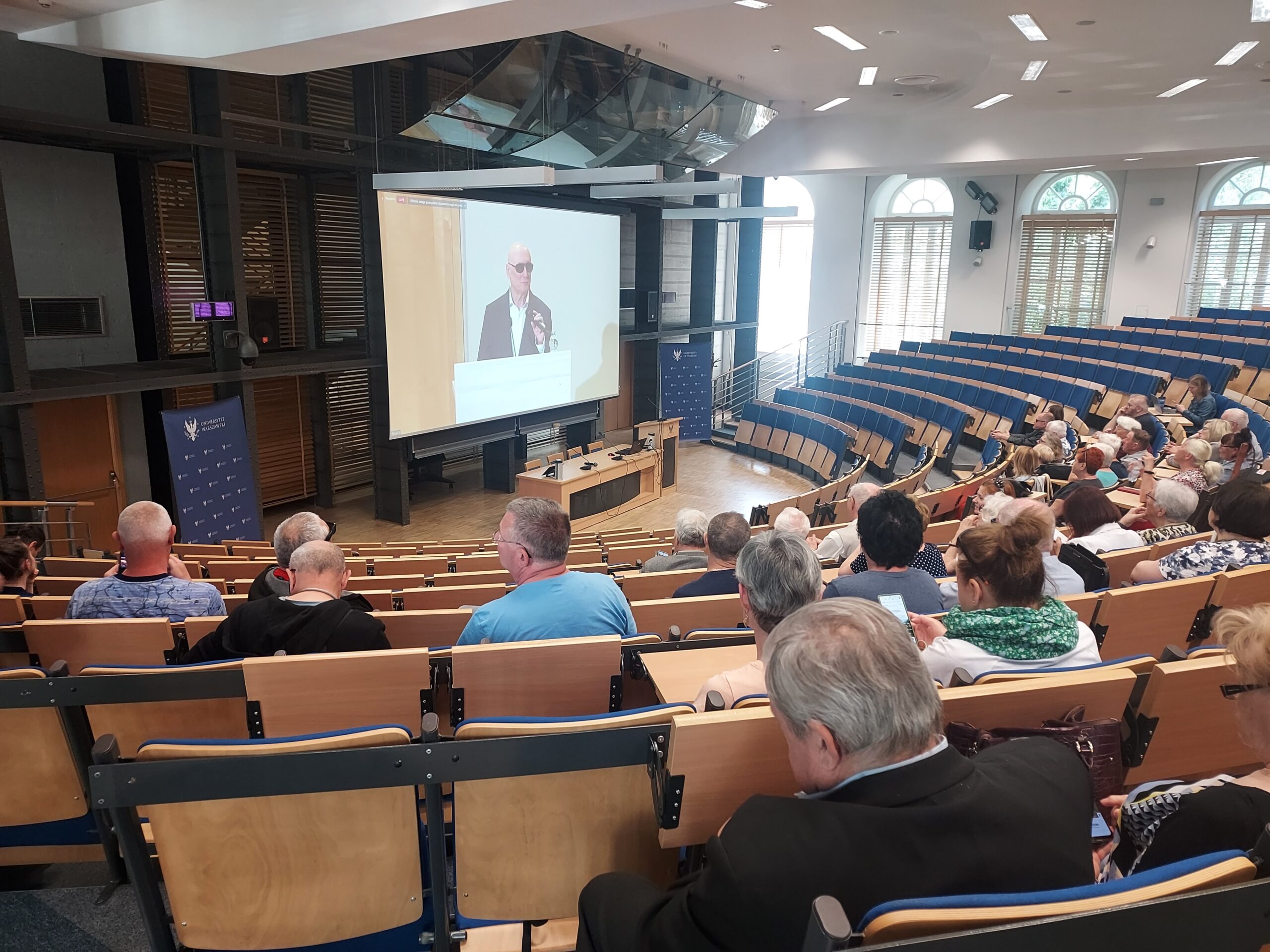 Transmisja przemówienia Marka Kalbarczyka w auli konferencyjnej UW