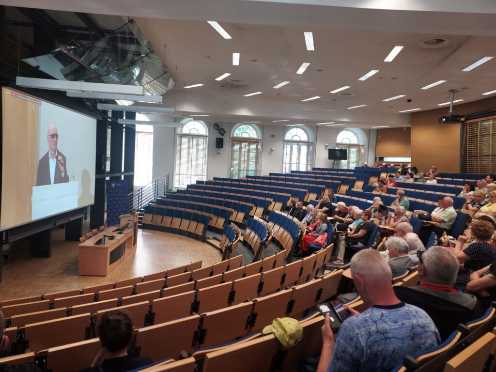 Uczestnicy konferencji REHA słuchają transmisji online w auli UW