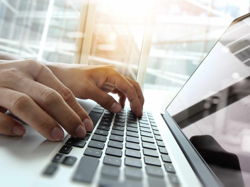 Ręce na klawiaturze laptopa w trakcie pracy.