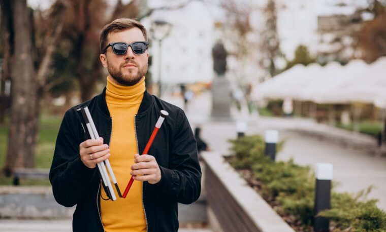 Młody mężczyzna rozkłada białą laskę.