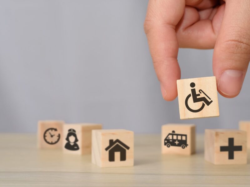 Palce układają klocki z ikonami dostępności.