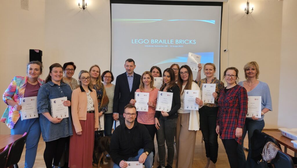 Uczestnicy szkolenia LEGO BRAILLE BRICKS wraz z prezesem ZG PZN. Uczestnicy w rękach trzymają certyfikaty ukończenia szkolenia,
