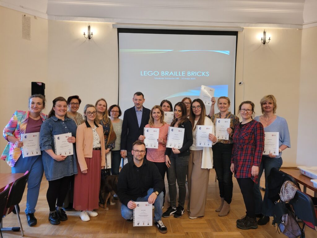 Uczestnicy szkolenia LEGO BRAILLE BRICKS wraz z prezesem ZG PZN. Uczestnicy w rękach trzymają certyfikaty ukończenia szkolenia,