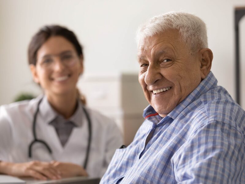 Pacjent, starszy pan - uśmiecha się rozmawiając lekarką w gabinecie lekarskim.