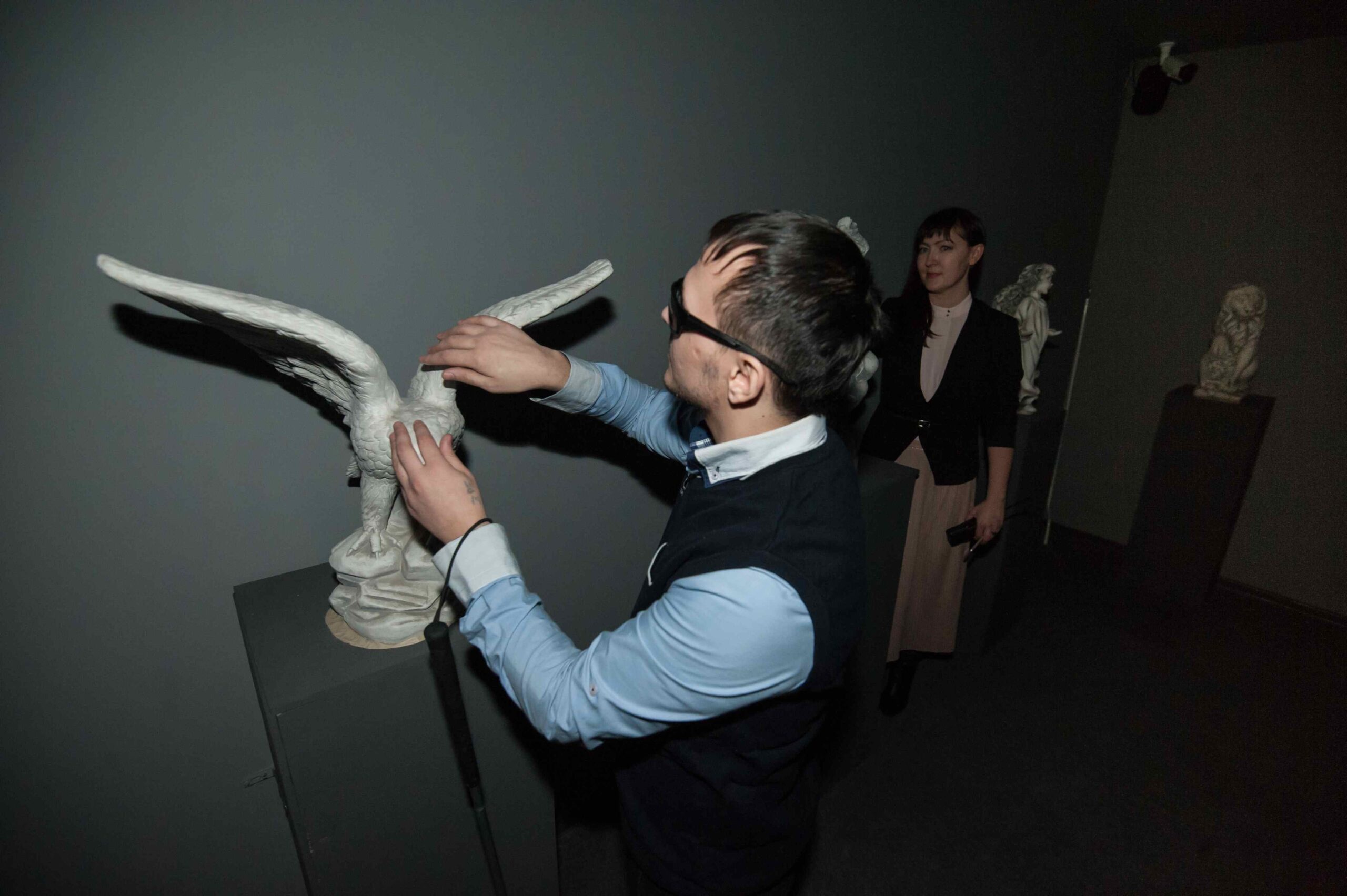 Niewidomy mężczyzna dotyka makiety ptaka, która umieszczona jest w sali muzealnej.