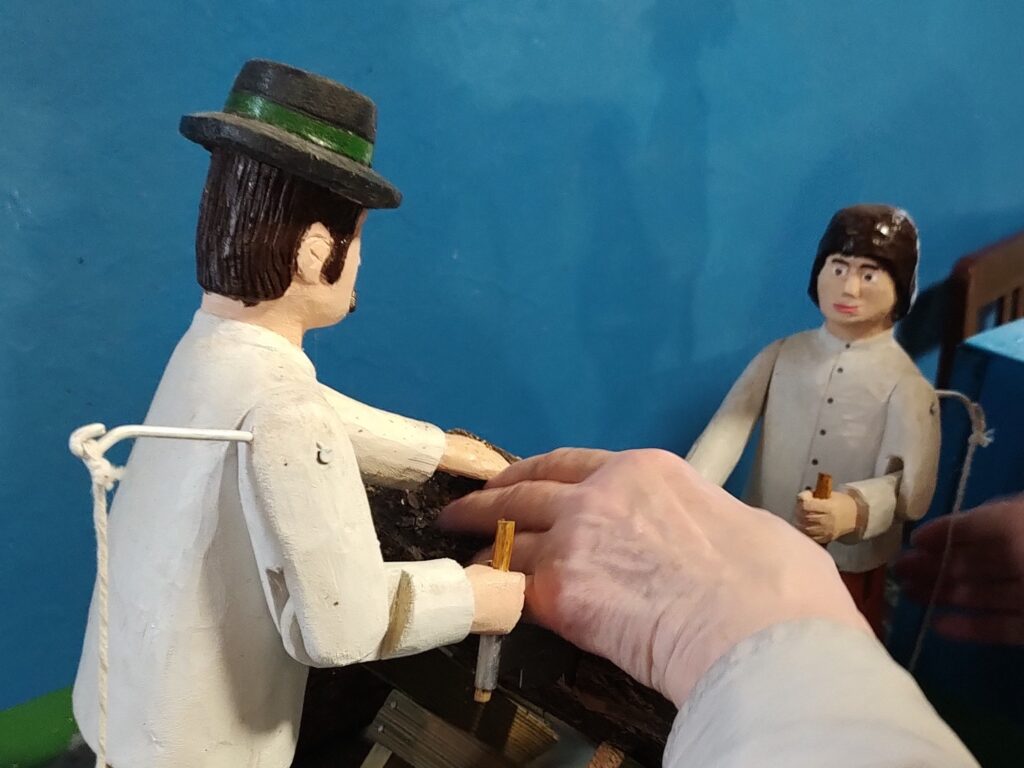 Palce dotykają rzeźby ludowej.