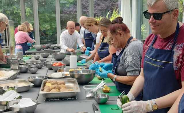 Uczestnicy projektu przygotowują potrawę w trakcie warsztatów kulinarnych.