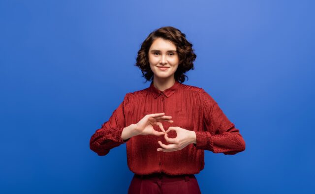 Młoda dziewczyna pokazuje jakiś znak palcami.