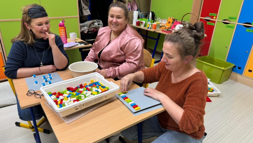 Trzy uśmiechnięte uczestniczki warsztatów przy stoliku z klockami LBB.