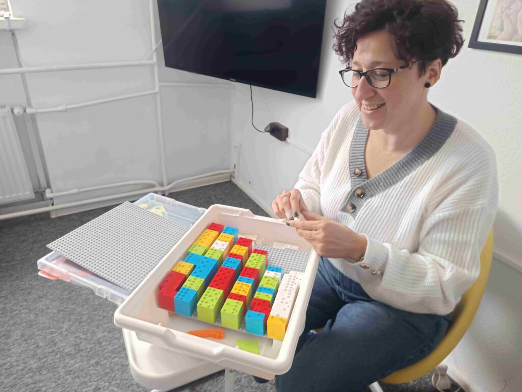 Koordynatorka projektu Lego Braille Bricks w PZN pokazuje klocki.