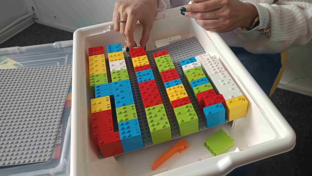 Palce dotykają klocków Lego Braille Bricks.