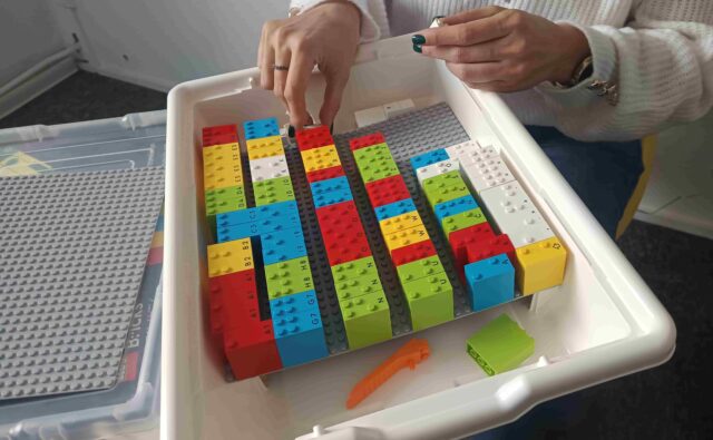 Palce dotykają klocków Lego Braille Bricks.