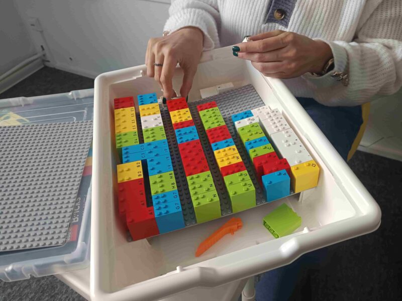 Palce dotykają klocków Lego Braille Bricks.