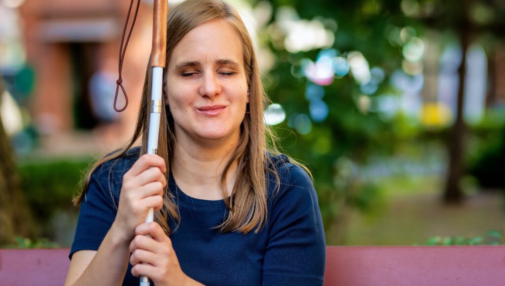 Na zdjęciu: niewidoma kobieta na ławce w parku.