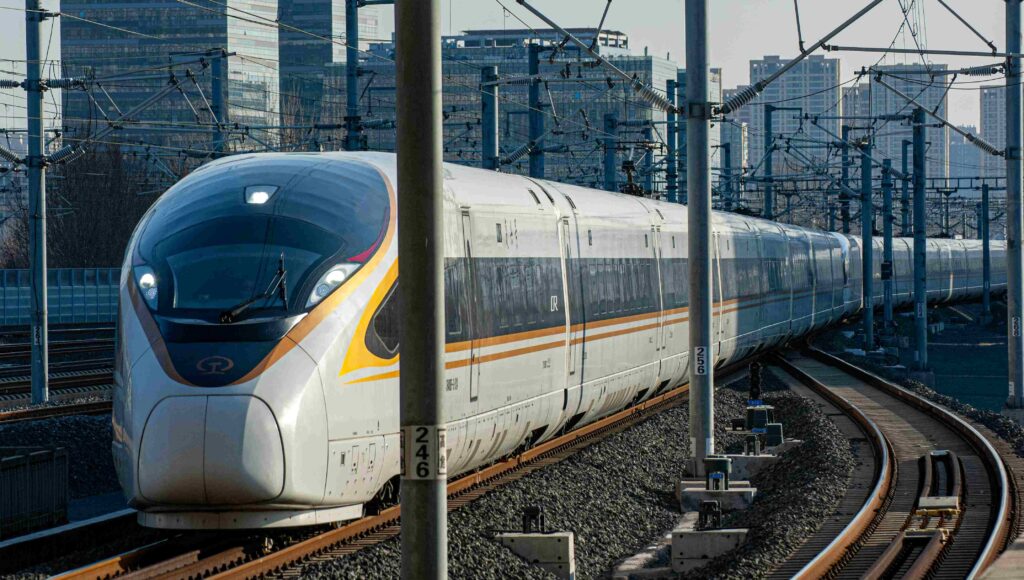 Pociąg jadących po torach, w tle budynki.