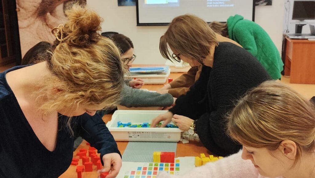 Uczestnicy szkolenia układają klocki LEGO BRAILLE BRICKS.