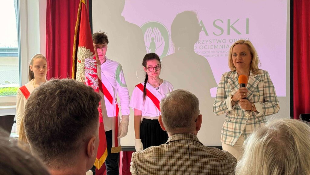 Mazowiecka kurator oświaty przemawia do zebranych, w tle trójka uczniów.