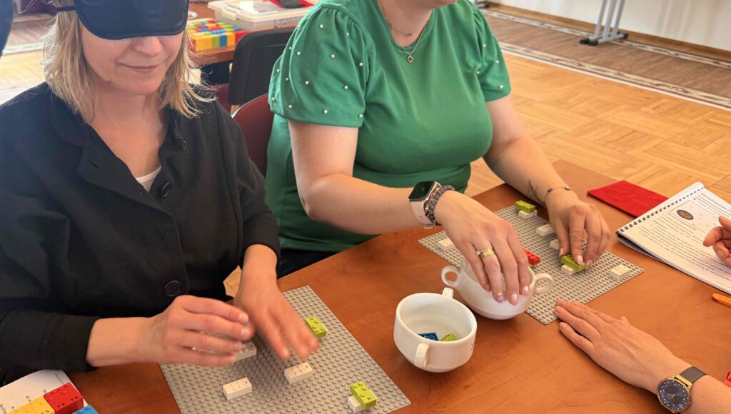 Uczestniczki warsztatów układają klocki LEGO BRAILLE BRICKS.