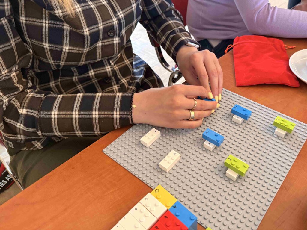 Uczestniczka warsztatów układa klocki LEGO BRAILLE BRICKS.